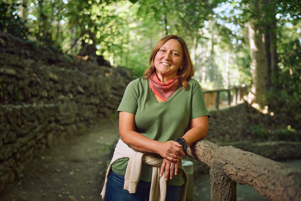 Traci Samczyk, a white woman in late middle age, stands on a Griffith Park hiking trail